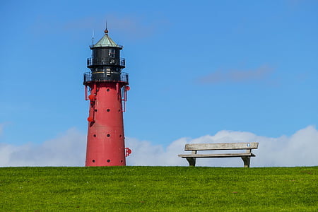 red and black lighthouse near on gray bench on grass field thumbnail