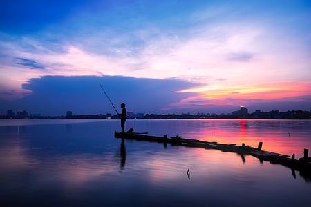 Silhouette man fishing in lake thumbnail