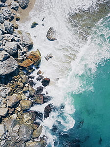 aerial view photography of rocks near sea waves at daytime thumbnail