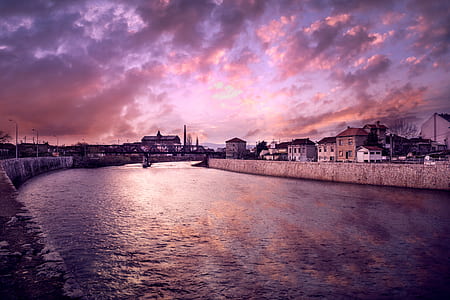 body of water between buildings in front of bridge thumbnail
