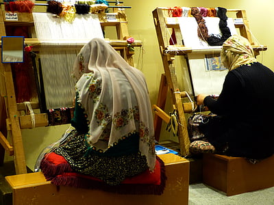 two women weaving sitting on brown wooden step stools thumbnail