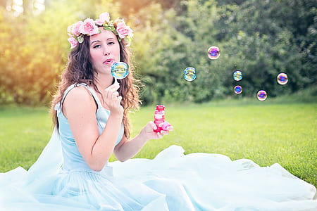woman wearing teal sleeveless maxi dress holding bubble maker during daytime thumbnail