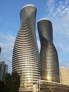 glass high-rise twist tower under white and blue cloudy skies thumbnail