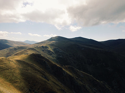 grass covered mountain under white clouds thumbnail