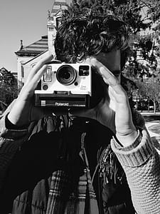 grayscale photo of man using Polaroid camera thumbnail