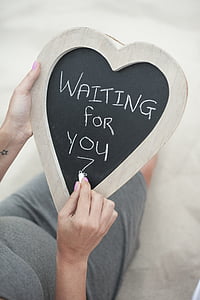 person writing a waiting for you in heart-shaped board thumbnail