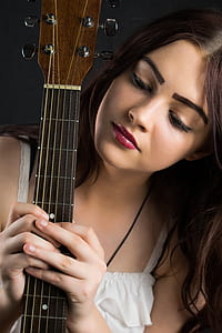 woman staring at black guitar neck while holding with both hands thumbnail