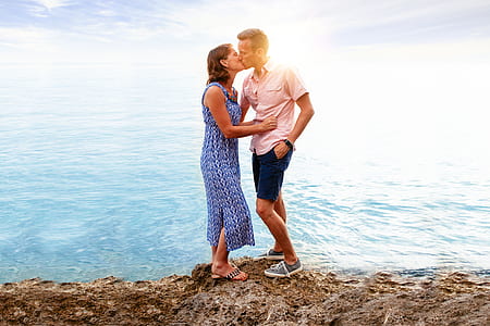 man and woman standing while kissing near body of water thumbnail