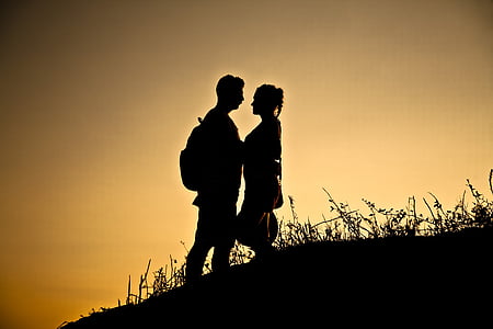 silhouette of man and woman on hill at golden hour thumbnail