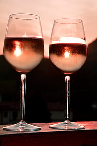 selective focus photography of 2 long-stem wine glasses with liquids during golden hour thumbnail