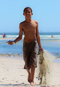 boy holding fish and net near seashore thumbnail