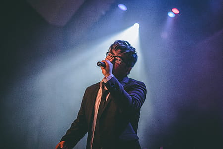 Man Holding Microphone on Stage thumbnail