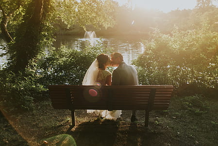 married couple kissing on bench in front of river thumbnail