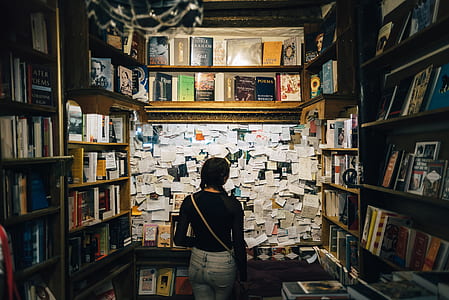 woman in black long-sleeved shirt wearing brown leather sling bag looking on white papers inside library thumbnail