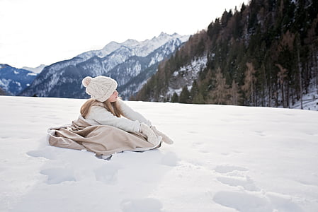 girl wearing winter coat sitting on snow field thumbnail