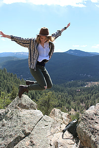 photo of woman jumping beside cliff during daytime thumbnail