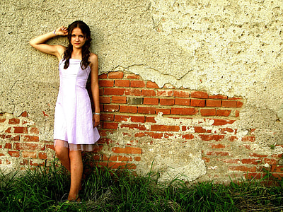 woman in pink strapless dress leaning on red bricks wall thumbnail