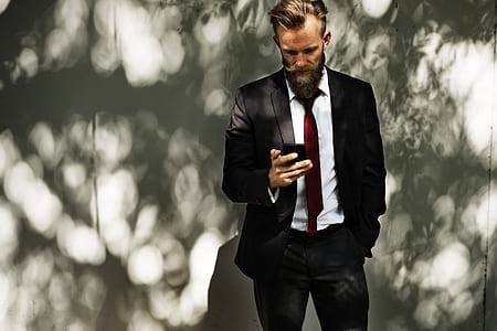 photo of man wearing black suit jacket with dress pants and white dress shirt holding phone thumbnail