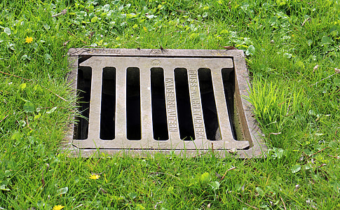 gray steel sewer grill cover surrounded by grass thumbnail