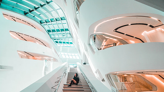 woman sitting on the stairs inside white concrete building thumbnail
