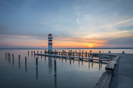 white and red lighthouse near body of water during daytime thumbnail