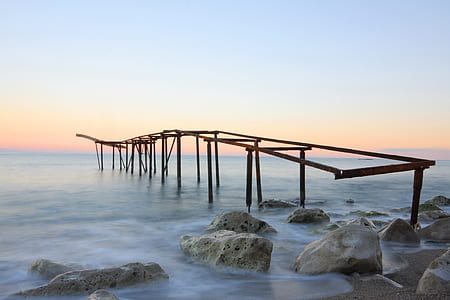 brown wooden bridge frame near rocky shore thumbnail