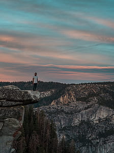 photography of person standing of top of rock formation thumbnail