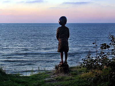 boy standing on cliff overlooking sea during daytime thumbnail