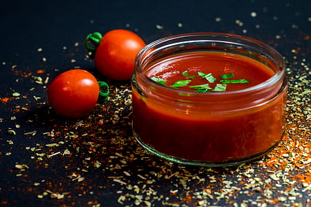 two red tomatoes near bowl of red sauce thumbnail