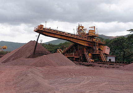 orange heavy equipment in red quarry during cloudy daytime thumbnail