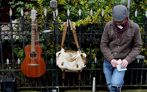 brown acoustic guitar hanging on black steel fence thumbnail
