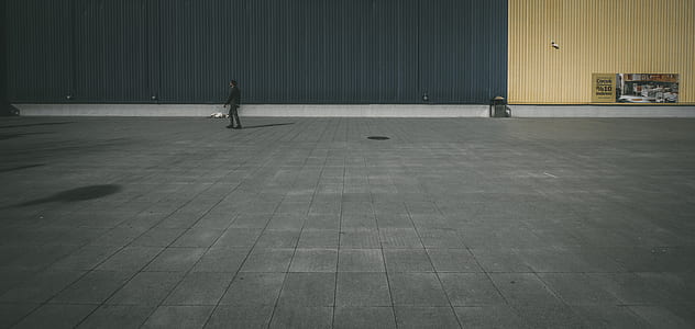 person standing on gray concrete flooring near building during daytime thumbnail