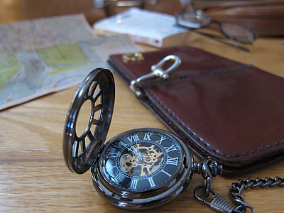 round silver pocket watch near brown patent leather wallet on table thumbnail
