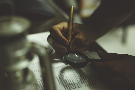 person holding pen and magnifying glass thumbnail