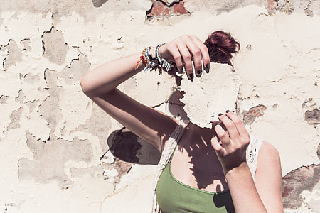 woman in green sleeveless top holding white tool during daytime near wall thumbnail
