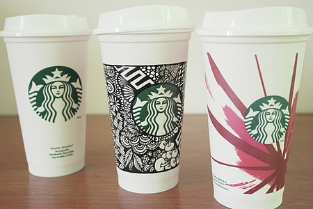 three Starbucks tumblers on brown wooden surface thumbnail