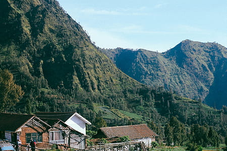 brown painted house beside mountain during daytime thumbnail