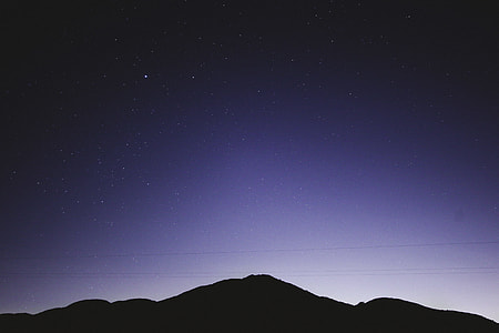 silhouette photography of mountain under stars at nighttime thumbnail