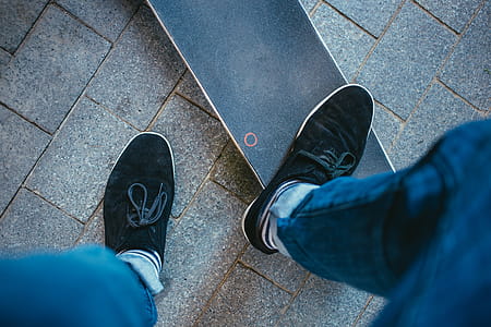 A skater wearing sneakers stepping on a skateboard deck thumbnail