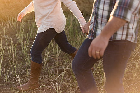 woman and man holding hands while walking through grass thumbnail