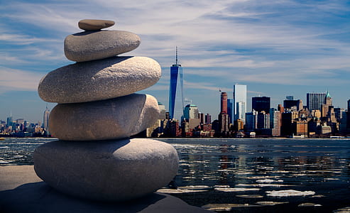 pile of stone near body of water with One World Trade Center building on background under cloudy sky at daytime thumbnail