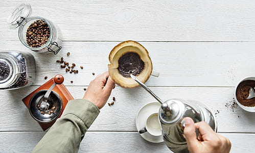 Person Pouring Hot Water in Mug With Ground Coffee thumbnail