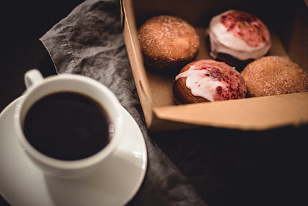 doughnuts in box beside mug filled with black liquid thumbnail