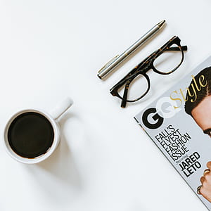 eyeglasses between pen and magazine on white board thumbnail