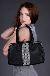 photo of woman wearing gray sleeveless top holding black leather handbag thumbnail