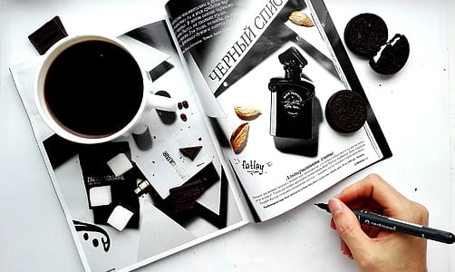 person holding black pen near magazine thumbnail