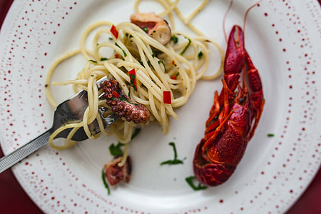 Fancy dinner with seafood pasta, crayfish and red wine by the table decorated with roses thumbnail