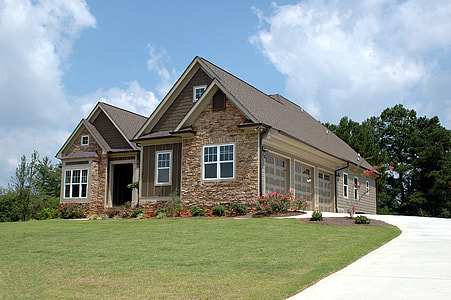 brown brick frame house surround with flowers in front of tall trees thumbnail