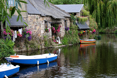 blue boat docked near gray stone house thumbnail