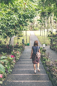 woman walking down the stairs near flowers during day thumbnail